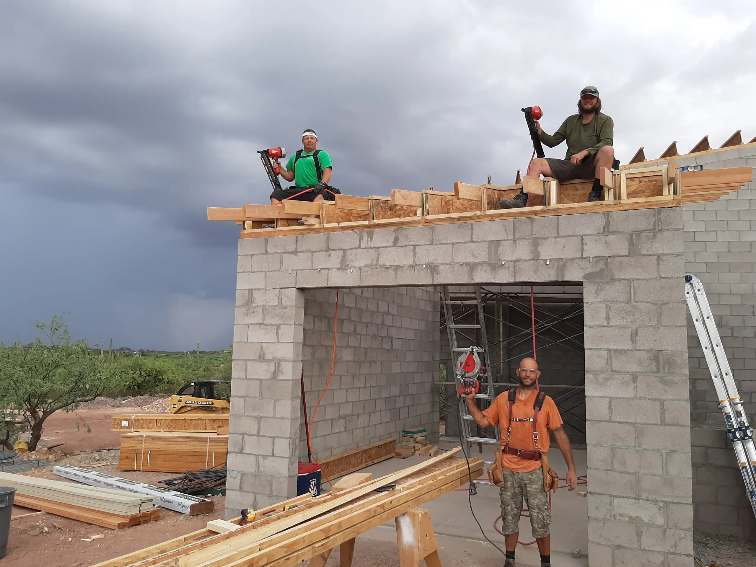 Construction workers building concrete structure with nail guns and lumber